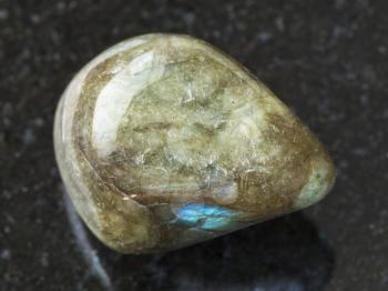 macro shooting of natural mineral rock specimen - polished labradorite gem stone on dark granite background from Finland