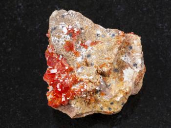 macro shooting of natural mineral rock specimen - rough crystal of Vanadinite gemstone on dark granite background from Morocco