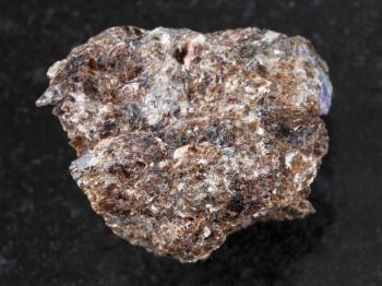 macro shooting of natural mineral rock specimen - rough Phlogopite stone with corundum crystal on dark granite background from Tajikistan
