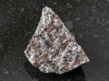 macro shooting of natural mineral rock specimen - raw spreusteined urtite stone on dark granite background from Khibiny Mountains, Kola Peninsula, Russia