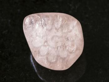 macro shooting of natural mineral rock specimen - tumbled morganite (pink beryl) gemstone on dark granite background from Ural Mountains, Russia