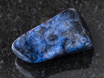 macro shooting of natural mineral rock specimen - polished dumortierite gem on dark granite background