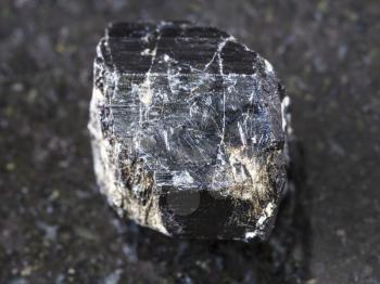 macro shooting of natural mineral rock specimen - raw crystal of Schorl (black tourmaline) gemstone on dark granite background from Madagascar