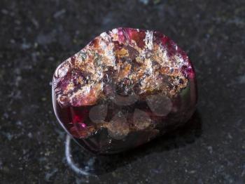 macro shooting of natural mineral rock specimen - broken red garnet gemstone on dark granite background