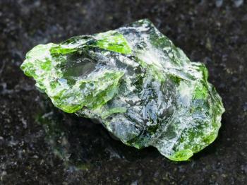 macro shooting of natural mineral rock specimen - raw crystal of Chrome Diopside gemstone on dark granite background from Inagli (Inaglinskoe mine) in Yakutia, Siberia, Russia