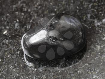 macro shooting of natural mineral rock specimen - polished black obsidian gem stone on dark granite background from Mexico