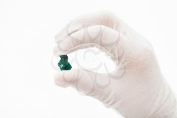 fingers in white glove holds dioptase crystal on white background