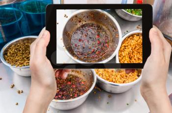 travel concept - tourist photographs bowl with spicy sauce on kitchen table in chinese eatery in Longsheng town in China on tablet