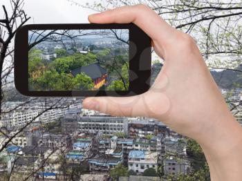 travel concept - tourist photographs above view of Guilin city in China in spring evening on smartphone