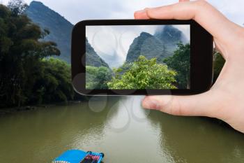 travel concept - tourist photographs river and karst peaks near Xingping town in Yangshuo county in spring season in China on smartphone