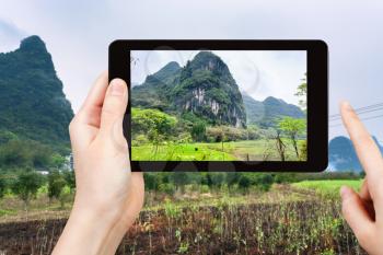 travel concept - tourist photographs gardens near karst mountains in Yangshuo County in spring season in China on smartphone -