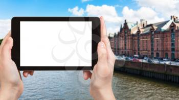 travel concept - tourist photographs houses on banks of Binnenhafen canal in Hamburg city in Germany in september on tablet with cut out screen for advertising logo