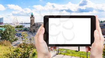 travel concept - tourist photographs fish market on St Pauli Landungsbrucken (Sankt Pauli Piers) landing place in Port of Hamburg in september on tablet with cut out screen for advertising logo