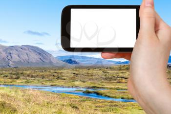 travel concept - tourist photographs panorama of valley in Thingvellir national park in autumn in Iceland on smartphone with cut out screen for advertising logo