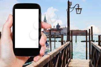 travel concept - tourist photograps San Giorgio Maggiore island from pier in Venice city in Italy in spring on smartphone with cut out screen for advertising logo