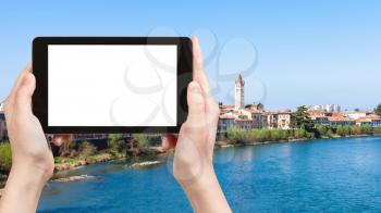 travel concept - tourist photographs waterfront of Adige river in Verona city in spring on tablet with cut out screen for advertising logo