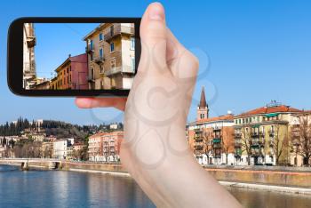 travel concept - tourist photographs urban houses in Verona city in Italy in spring on smartphone