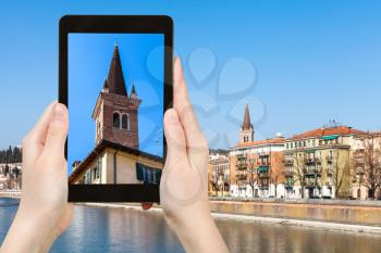 travel concept - tourist photographs tower of church Chiesa di San Tomaso Becket (Chiesa di San Tomaso Cantuariense) over urban house in Verona city in Italy in spring on tablet