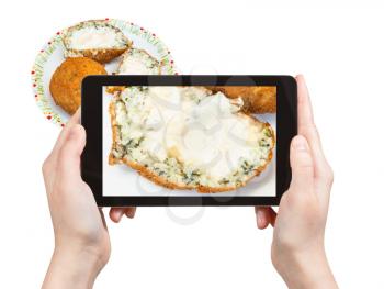 travel concept - tourist photographs spinach stuffed rice balls arancini on plate (traditional sicilian street food) in Sicily Italy on tablet isolated on white background