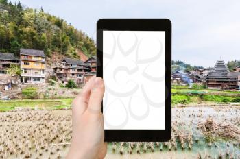 travel concept - tourist photographs rice paddy in Chengyang village of Sanjiang Dong Autonomous County in China in spring on tablet with cut out screen for advertising logo