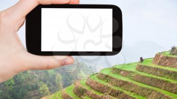 travel concept - tourist photographs Rice Terraces in Dazhai Longsheng (Dragon's Backbone, Longji) county in China in spring on smartphone with cut out screen for advertising logo