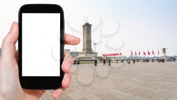 travel concept - tourist photographs the Monument of the People's Heroes on Tiananmen Square in Beijing city in China on smartphone with cut out screen for advertising logo