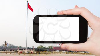 travel concept - tourist photographs flagpole on Tiananmen Square in Beijing city in China on smartphone with cut out screen for advertising logo
