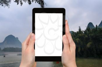 travel concept - tourist photograps river near Xingping town in Yangshuo county in China in spring morning on tablet with cut out screen for advertising logo