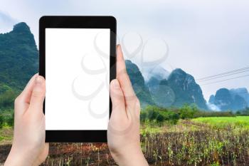 travel concept - tourist photographs gardens near karst mountain in Yangshuo County in China in spring season on smartphone with cut out screen for advertising logo