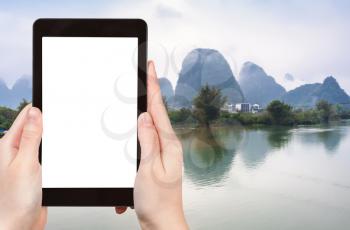 travel concept - tourist photograps water of Yulong and Jinbao rivers and karst peaks in Yangshuo County in China in spring on tablet with cut out screen for advertising logo
