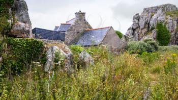 travel in France - typical Breton stone house and rocks in Plougrescant town of the Cotes-d'Armor department in Brittany in rainy summer day