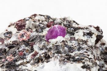 macro shooting of natural mineral rock specimen - corundum crystal in gneiss stone close up on white marble background from Hit-island of Upper Pulongskoye Lake, Karelia in Russia