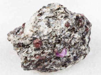 macro shooting of natural mineral rock specimen - rough corundum crystals in gneiss stone on white marble background from Hit-island of Upper Pulongskoye Lake, Karelia in Russia