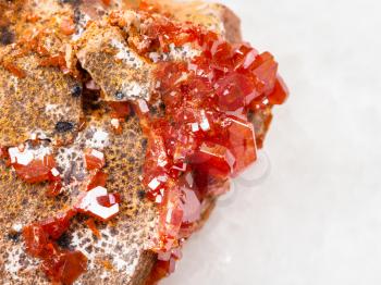 macro shooting of natural mineral rock specimen - crystals of Vanadinite stone close up on white marble background from Morocco