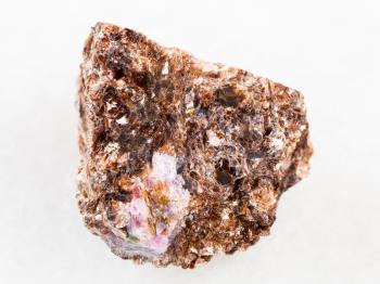 macro shooting of natural mineral rock specimen - raw Phlogopite stone with corundum crystal on white marble background from Tajikistan