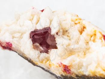 macro shooting of natural mineral rock specimen - red crystal of Cinnabar close up in rough Carbonatite stone on white marble background from North China