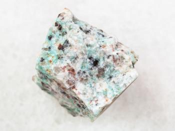 macro shooting of natural mineral rock specimen - rough amazonite granite stone on white marble background