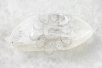 macro shooting of natural mineral rock specimen - tumbled Natrolite gemstone on white marble background from Lovozero Massif, Kola peninsula, Russia