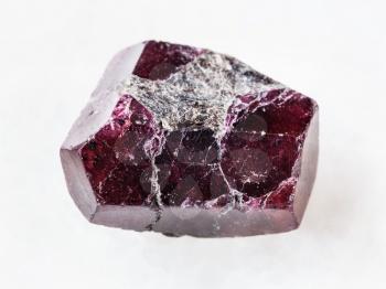 macro shooting of natural mineral rock specimen - rough crystal of red garnet gemstone on white marble background