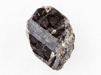macro shooting of natural mineral rock specimen - raw crystal of Schorl (black tourmaline) gemstone on white marble background from Madagascar