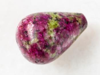 macro shooting of natural mineral rock specimen - polished pink and green zoisite gemstone on white marble background