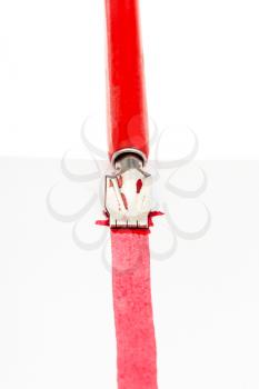 red dip pen draws a red line on sheet of paper by wide nib close up isolated on white background