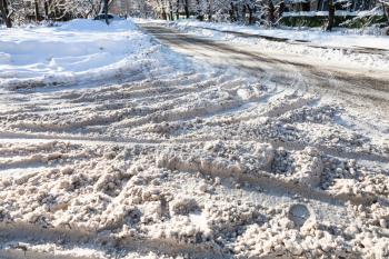 surface of snow-covered slippery urban road in sunny winter day