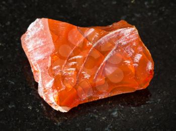 macro shooting of natural mineral - rough fire opal gemstone on black granite from Ural Mountains