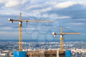 cranes at top of skyscraper under construction in Moscow city in autumn day