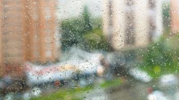 rain drops on window glass and blurred street on background on rainy autumn day