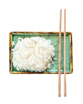 top view of portion of boiled rice and chopsticks on green plate isolated on white background