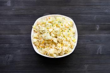 Chinese cuisine dish - top view of bowl with Fried Rice with Shrimps, Vegetables and Eggs (Yangzhou rice) on dark wooden board