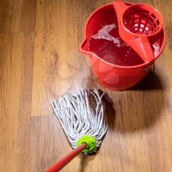 point of view of rope mop near bucket with water on wooden laminate floor at home