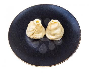 two cooked Buuz (Mongolian dumpling filled with minced meat) on dark brown plate isolated on white background